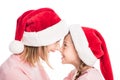 Smiling mother and daughter wearing santa hats touching noses, Royalty Free Stock Photo