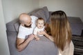 Smiling mother and father holding their baby girl daughter sitting on bed at home. Happy family concept, Bearded man in Royalty Free Stock Photo