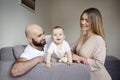 Smiling mother and father holding their baby girl daughter sitting on bed at home. Happy family concept, Bearded man in Royalty Free Stock Photo