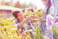 Smiling mother giving flowers to daughter while gardening at farm