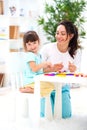 Smiling mother helps a little daughter to sculpt figurines from plasticine. Children`s creativity. Happy family