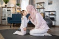 Smiling mother and her adorable little daughter relaxing after sports sitting on the mat Royalty Free Stock Photo