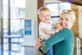 Smiling mother holding baby boy at the lobby in the hotel Royalty Free Stock Photo