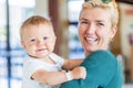 Smiling mother holding baby boy at the lobby in the hotel Royalty Free Stock Photo