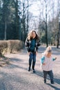 Smiling mother leaned forward watching little girl walking down the road