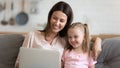 Smiling mother and little daughter using laptop together close up Royalty Free Stock Photo