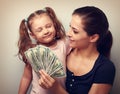 Smiling mother looking on happy daughter holding cash of dollars Royalty Free Stock Photo