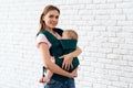 Smiling mother with newborn baby in baby sling.