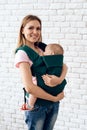 Smiling mother with newborn baby in baby sling. Royalty Free Stock Photo