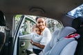 Smiling mother putting baby daughter in a car seat Royalty Free Stock Photo