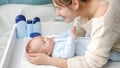 Smiling mother stroking and smiling at her little baby boy lying on dressing table at bedroom. Concept of hygiene, baby Royalty Free Stock Photo