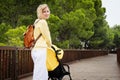 Smiling mother strolling with newborn in carriage