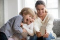 Smiling mother taking selfie with two cute kids on smartphone