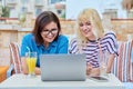 Smiling mother and teenage daughter looking into laptop screen together Royalty Free Stock Photo