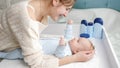 Smiling mother tickling and playing with her little baby son lying on dressing table at bedroom. Concept of hygiene Royalty Free Stock Photo