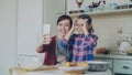 Smiling mother together with funny daughter taking selfie photo with smartphone camera making silly face while cooking Royalty Free Stock Photo