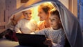 Smiling mother with two boys sitting in blanket tent in bed and using tablet computer. Family having time together, children with Royalty Free Stock Photo