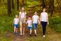 Smiling mothers and children holding hands. Big happy family, two women and three children in white t-shirts Royalty Free Stock Photo