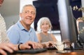 Smiling motivated older man using computer at internet cafe