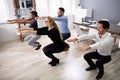 Young Businesspeople Doing Sit-ups In Office Royalty Free Stock Photo