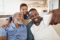 Smiling multi-generation family taking selfie from mobile phone in living room Royalty Free Stock Photo