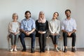 Smiling multicultural professional business people sit on chairs in row Royalty Free Stock Photo