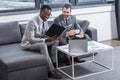 smiling multiethnic businessmen sitting on couch and having discussion