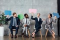 Smiling multiethnic businesspeople holding speech bubbles and thought bubble while sitting in Royalty Free Stock Photo