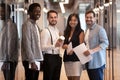 Smiling multiethnic colleagues posing for picture in office hallway