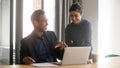 Smiling multiethnic diverse colleagues talk cooperating at laptop