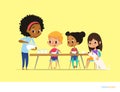 Smiling multiracial children sit at table and have breakfast while mother pour milk into gasses. Kids eating healthy morning meal. Royalty Free Stock Photo