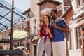 Smiling multiracial couple taking selfie on smartphone using selfiestick in the city at daytime