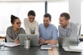 Smiling multiracial employees work on laptop in office