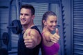 Smiling muscular couple gesturing thumbs up