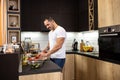 Smiling muscular man in the kitchen slicing a tomato with a chef knife as he prepares salad Royalty Free Stock Photo