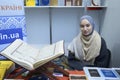 Smiling muslim girl wearing hijab presenting islamic literature in the bookshop, Quran placed on the counter