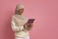 Smiling Muslim Woman In Hijab Using Digital Tablet, Standing Over Pink Background Royalty Free Stock Photo