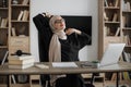 Smiling muslim woman relaxing by stretching her body while sitting in front of pc computer laptop Royalty Free Stock Photo