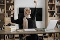 Smiling muslim woman relaxing by stretching her body while sitting in front of pc computer laptop Royalty Free Stock Photo