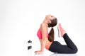 Smiling natural sportswoman with bottle of water doing stretching exercises