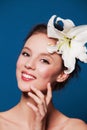 Smiling natural woman with the lily flower on blue Royalty Free Stock Photo