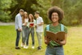 Smiling Nerd Black Girl Posing With Book Outdoors At Campus