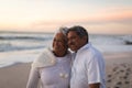 Smiling newlywed senior biracial couple looking away at beach against sky during sunset Royalty Free Stock Photo