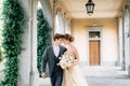 Smiling newlyweds embrace while walking along the terrace with columns against the backdrop of greenery. Lake Como Royalty Free Stock Photo
