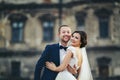 Smiling newlyweds hug in the front of an old castle