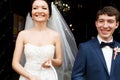 Smiling newlyweds stand in the front of the church Royalty Free Stock Photo