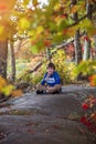 Smiling nine year old boy sitting outside in Autumn with colorful fall trees Royalty Free Stock Photo