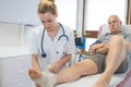 Smiling nurse bandaging leg patient in hospital Royalty Free Stock Photo