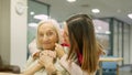 Smiling nurse embracing a senior woman in geriatrics