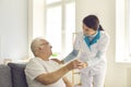 Smiling nurse giving glass of water to senior man in nursing home or assisted living facility